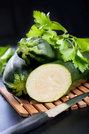 Green zucchini and half with parsley on black backgroundの写真素材