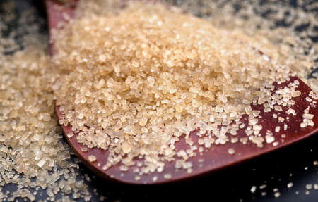 Closeup of brown granulated sugar on a wooden spoon  の写真素材