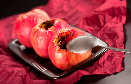 Baked red apples with cinnamon on black plateの写真素材