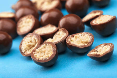 Chocolate balls and halves with crisp filling on blue backgroundの写真素材