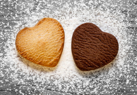 Two heart shaped cookies on grey wooden background. Baked butter and chocolate cookies. Valentines day concept. Top view.の写真素材