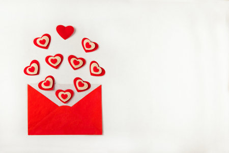 Open red envelope with lots of different red hearts coming out and spread over the white background as love letter. Valentines Day concept. Top view, Flat layの写真素材