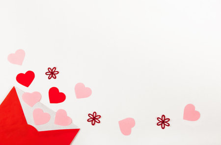 Open red envelope with lots of different red and pink hearts coming out and spread over the white background as love letter. Valentines Day concept. Top view, Flat layの写真素材