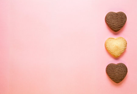 Three baked heart shaped cookies on pink background. Top view, empty space for text. Valentines day concrpt. Flat layの写真素材