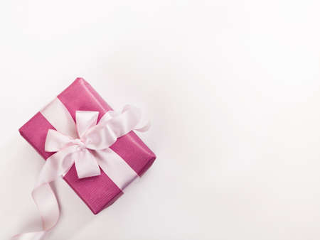 Pink gift box, white bow, lcurved ribbon and empty space for text on white background. Holiday greeting background or invitation. Copyspace.の写真素材