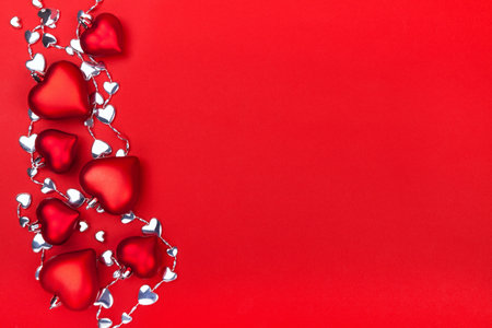 Valentines Day greeting card with red and shiny hearts on red background. Top view with empty space for your text. Flat lay, copy spaceの写真素材