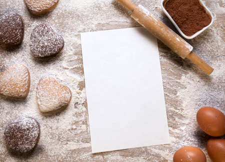 Baking background with blank sheet of paper for the recipe or menu, heart shaped cookies, eggs, flour and rolling pin. Empty space for text. Valentines dayの写真素材