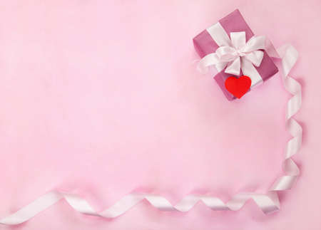 Pink gift box, white bow, long curved ribbon, paper red heart and empty space for text. Top view, flat lay. Valentines Day, Wedding day, birthday, Mothers Day greeting background or invitationの写真素材
