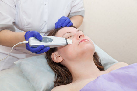 Caucasian woman receiving ultrasonic facial peeling with professional equipment in spa salon. Cosmetology and skin care. Beauty treatment, cleansing procedureの写真素材
