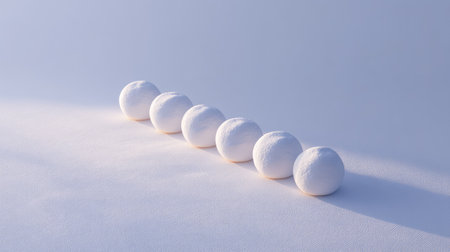 A visually striking arrangement of white spheres on a soft fabric surface, showcasing light and shadow interplay in a minimalist setting perfect for artistic projects.の素材