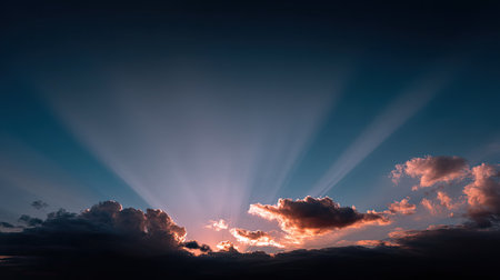 Experience the beauty of a serene sunset where dramatic rays of light pierce through colorful clouds in a deep blue sky, creating a peaceful atmosphere.の素材