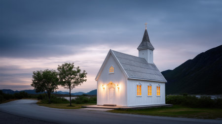 A peaceful white church stands by the roadside, illuminated softly at dusk. Surrounded by nature and mountains, it evokes tranquility and serenity in a rural setting.の素材