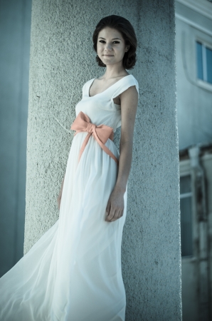 Girl by the column  Beautiful girl in white dress with red bow-knot on her waist の写真素材
