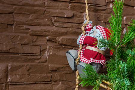 Christmas composition of a Christmas tree and Santa Claus climbing a ropeの写真素材