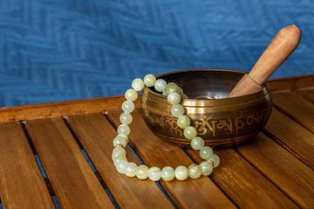 Tibetan singing bowl and jade beads on a wooden standの写真素材
