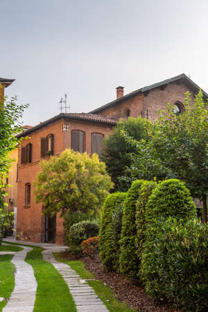 Old houses with tiled roofs and turrets against a cloudy sky in Milan, Italyの写真素材