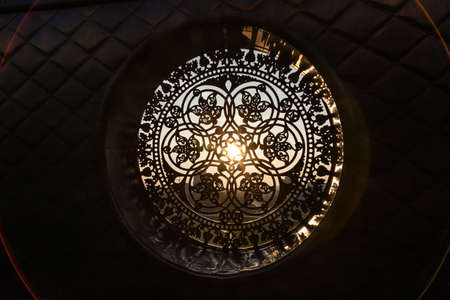The sun's rays make their way through the cast-iron forged decorative lattice.の写真素材