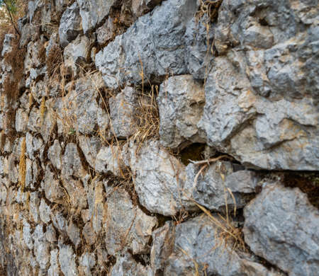 Ancient stone masonry wall overgrown with grass in Greeceの写真素材