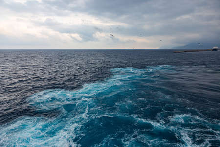wake in blue water leaving port of Savona, Italyの写真素材