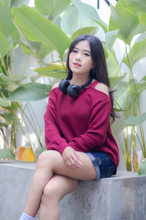 Portrait of thai china adult beautiful girl Red sweater blue jeans relax and smileの写真素材