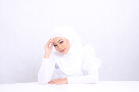 portrait charm Beautiful adult woman hijab smile look at camera hands on white table and touch forehead isolated white background. concept of cosmetics, health, skin care, facial treatmentの写真素材
