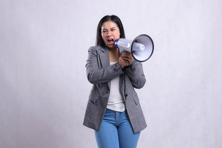 formal beautiful young lady screaming angry both hands holding megaphone loudspeaker forward wearing...