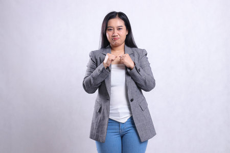 expression of beautiful adult woman pouting both hands clenched in front of chest wearing gray...