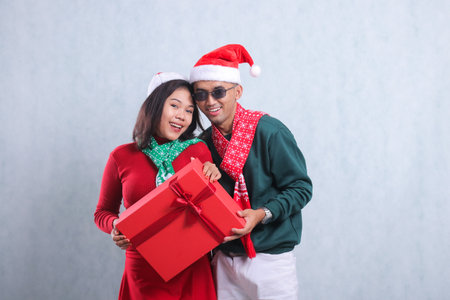portrait of a young couple asia wearing christmas sweaters, santa hats and scarves, cheerfully...