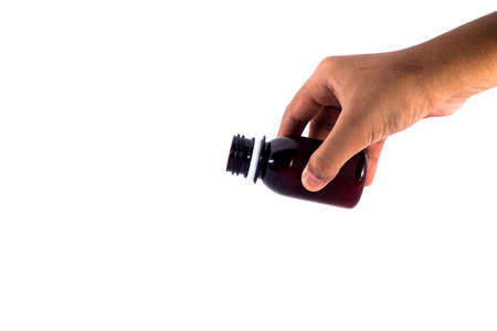 A hand holding a medicine bottle in action to puor the syrup into something isolated on white backgroundの写真素材