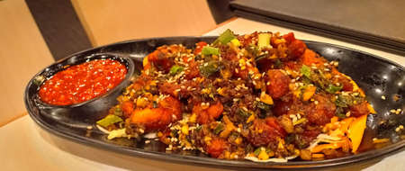 Paneer Manchurian or Paneer 65 in bowl at black concrete background. Paneer Manchurian is Indian Chinese cuisine dish with panner cheese, tomatoes, onion, soy sauce. Close Upの写真素材