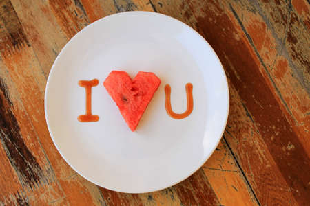 heart shaped watermelon in white dish on wood tableの写真素材