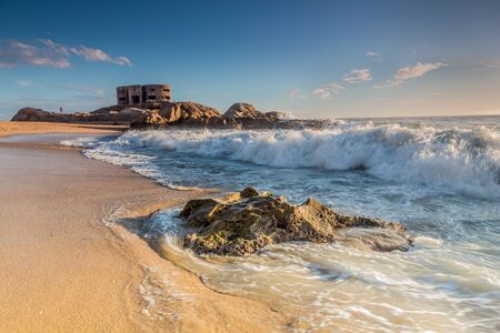 Big military bunker and waves crashing on beach shore in Cadiz, Spain