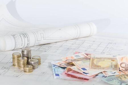 banknotes and coins over architectural plansの写真素材