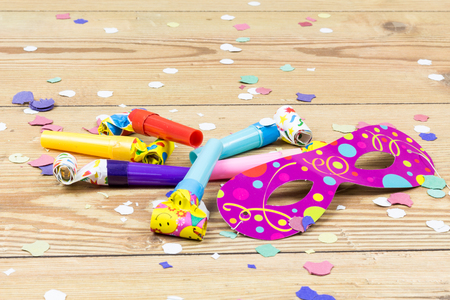confetti, mask and party blowers on wood backgroundの写真素材