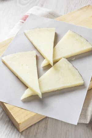 Manchego cheese on wooden board with olives, Spanish appetizer, Tapas.