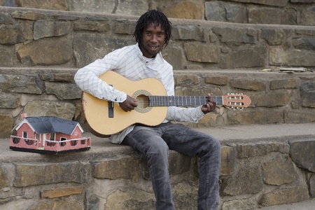 African busker in Howick, KwaZulu-Natal with ethnic model house collecting moneyの写真素材