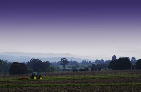 Farmer ploughing with tracker on farmland landscape