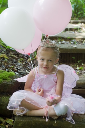 Little girl dressing up as a fairy-tale ballet princess on her birthday in forest gardenの写真素材