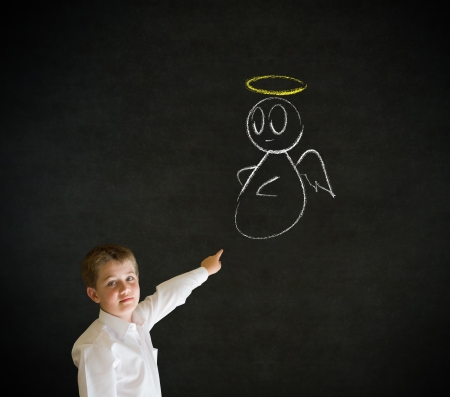 Pointing boy dressed up as business man with chalk angel on shoulder making decision on blackboard backgroundの写真素材