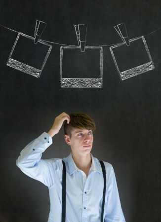 Businessman, teacher or student with chalk instant photograph style photographs on clothes line blackboard backgroundの写真素材