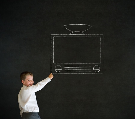 Writing boy dressed up as business man with chalk tv television on blackboard backgroundの写真素材