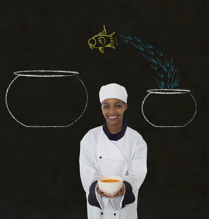 Woman female African or African American chef jumping fish decision on chalk blackboard backgroundの写真素材