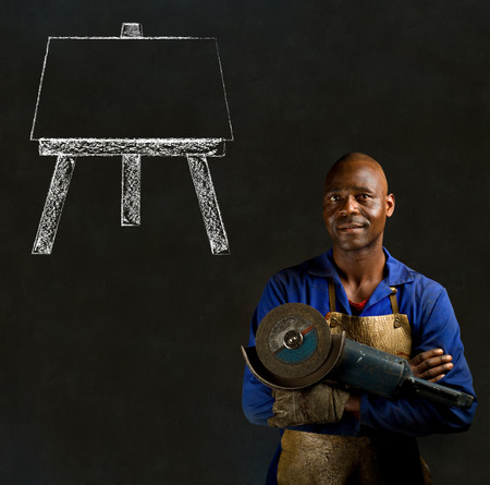 African black man industrial worker with chalk easel on blackboard backgroundの写真素材