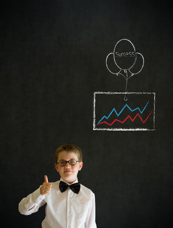 Thumbs up boy dressed up as business man with chalk success graph and balloon on blackboard backgroundの写真素材