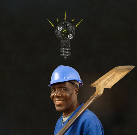 African American black man worker with a chalk gear cog lightbulb on a blackboard backgroundの写真素材