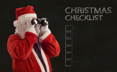 Father Christmas looking at the future business strategy with binoculars and checklist backboard backgroundの写真素材