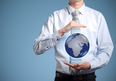 Businessman holds or holding world earth in the palm of handの写真素材