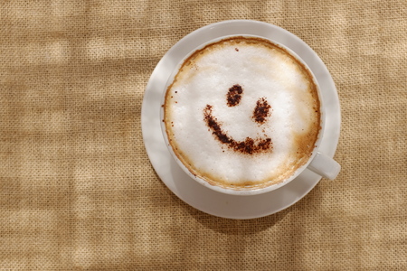 Coffee cappuccino with foam or chocolate smiling welcome happy face in restaurant or hotelの写真素材