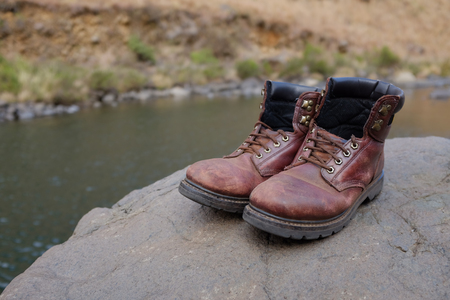 Pair of old hiking boots on rock at river or stream at Lotheni. KwaZulu-Natal in the South African...