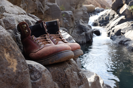 Pair of old hiking boots on rock at river, stream, waterfall at Lotheni. KwaZulu-Natal in the South African Drakensburg mountainsの写真素材